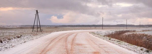 覆盖着白雪的乡间小路穿过田野 变压器杆 从车上俯瞰全景 五彩斑斓的云彩 戏剧性的日落 冬季轮胎 偏远村庄 — 图库照片