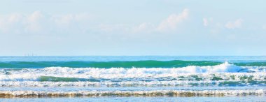 Douarnenez körfezinin kumlu sahilinden bir manzara. Açık mavi gökyüzü. Sudaki yansımalar. Dalgalar ve su sıçramaları. Brittany, Fransa. Seyahat yerleri, boş zaman etkinlik teması