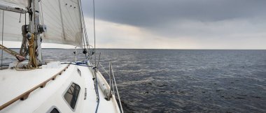 Beyaz yat dalgalı bir havada yelken açıyor güverteden pruva ve yelkenlere kadar yakın görüntü. Kuzey denizi, Norveç. Dramatik bulut manzarası. Yelkencilik, yarış, spor, eğlence, eğlence etkinliği teması