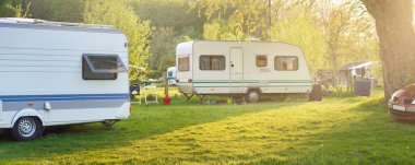 Kamp alanındaki yeşil çimlere park edilmiş bir karavan ve araba. Idyllic bahar manzarası. Hollanda. Karavan, ulaşım, yolculuk, tatiller, eko-turizm, seyahat, yaşam tarzı, dinlenme