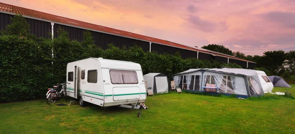 Kamp alanında bisikleti olan beyaz bir karavan. Bahar manzarası. Pembe günbatımı bulutları. Hollanda. Yaşam tarzı, özgürlük, seyahat, eko-turizm, yolculuk, dinlenme, ulaşım, karavan, karavan