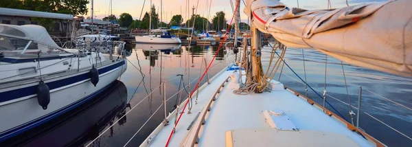 Günbatımında yat limanındaki bir rıhtıma demirlenmiş zarif ve modern yelkenli tekneler. Ulaşım, gezi, boş zaman aktivitesi, spor ve eğlence teması. İsveç