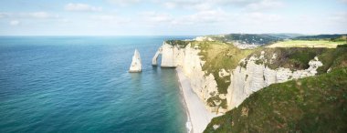 Gün batımında Etretat beyaz uçurumlarının manzaralı panoramik görüntüsü. Dramatik gökyüzü, gök mavisi su. Fransa, Normandiya 'da yaz tatili. Seyahat yerleri, ulusal dönüm noktaları, geziler, tarih.