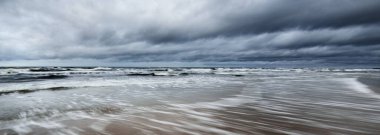 Kışın Kuzey Denizi 'nin yukarısında fırtına bulutları, uzun pozlama. Dramatik gökyüzü, dalgalar ve su sıçramaları. Koyu deniz manzarası. Hollanda