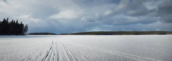 日没の凍った湖と松林 氷の質感 トラクターの近くを追跡します 劇的な青空 雲の風景 冬の不思議の国 生態系 気候変動 悪天候 — ストック写真