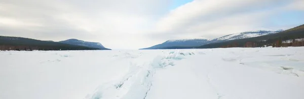 凍結湖の海岸に氷の圧力尾根 背景の山のピーク 劇的な雲景 絵のように美しい冬の風景 生態系 気候変動 地球温暖化の概念 カナダ — ストック写真