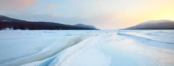 日没の凍った湖の海岸に氷の圧力尾根 背景の山のピーク カラフルな雲の風景 絵のように美しい冬の風景 生態系 気候変動 地球温暖化の概念 — ストック写真
