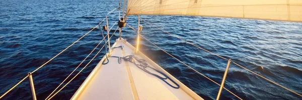 日落时 白色游艇在多加瓦河航行 从甲板到船头 桅杆和船帆 俯瞰全景 货轮和港口起重机在后面 拉脱维亚里加湾 — 图库照片