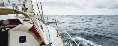 Bulutlu bir günde Kuzey Denizi 'nde yelken açan beyaz bir yat. Karanlık fırtına gökyüzü suya yansıyor. Rogaland bölgesi, Norveç. Spor, eğlence, eğlence etkinlik teması