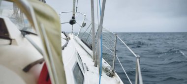 Fırtına sırasında yat gezintisi. Güverteden pruvaya yakın görüntü, direk, yelkenler. Dramatik gökyüzü, kara bulutlar, dalgalar, su sıçramaları. Kuzey denizi, Norveç. Destansı deniz manzarası. Kötü hava