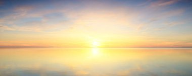 Baltık Denizi. Dramatik günbatımı gökyüzü, parlayan pembe ve altın bulutlar, suda simetri yansımaları. Soyut doğal desen, doku, arka plan. Resimli panoramik manzara