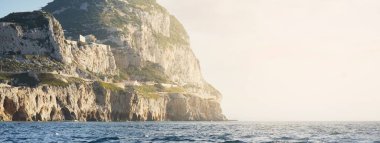 Europa Point 'in kayalık kıyıları (kayalıklar, dağlar), yelkenli teknenin manzarası. Cebelitarık, İngiliz Denizaşırı Bölgesi. Seyahat yerleri, ulusal dönüm noktası, gezi teması
