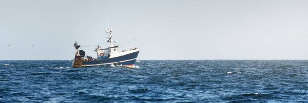 Маленькая рыбацкая лодка, плавающая в открытом Средиземном море, крупным планом. Вид с яхты. Отдых, спорт и отдых, пищевая промышленность, традиционные ремесла, экологические концепции ущерба