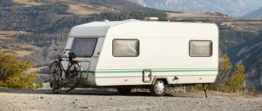 Karavan karavanı, bisiklet ve araba bir dağın tepesine park edilmiş. Fransız Alpleri 'nde, Lac de Serre-Poncon Gölü yakınlarında. Ulaşım, karavan, karavan, yol gezisi, kamp, turizm, eğlence, yaşam tarzı