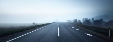 Gece sisli bir havada boş otobanın panoramik görüntüsü. Ay ışığı, temiz gökyüzü. Gün doğumu. Avrupa. Ulaşım, lojistik, seyahat, yolculuk, özgürlük, sürüş. Kırsal alan