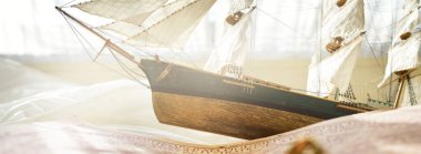 Retro stili altın antika pusula (güneş saati), ahşap uzun gemi ölçeği modeli ve eski beyaz deniz haritası yakın plan. Klasik natürmort. Yelkencilik, seyahat, yön bulma kavramları. Koleksiyon, hatıra, hediye.