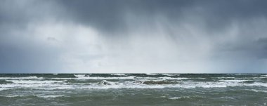Fırtına sonrası dramatik bulutların altında Baltık Denizi 'nin kumlu sahili. Letonya 'da sızıntı var. Destansı deniz manzarası. Kasırga, fırtına, sert hava, meteoroloji, iklim değişikliği, doğal fenomen