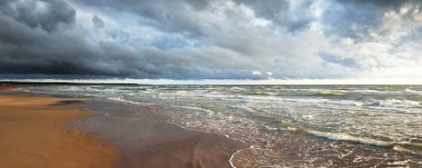 Sandy Baltık deniz kıyısı. Gün batımında fırtınadan sonra. Letonya 'da sızıntı var. Destansı deniz manzarası. Kasırga, fırtına, kararsız hava, meteoroloji, iklim değişikliği, doğal olay