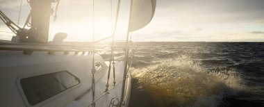 Gün batımında açık denizde yelken açmak. Güverteden pruvaya, direğe ve yelkenlere yakın görüntü. Dramatik fırtınalı gökyüzü, altın bulutlar, kış kasırgası, sert hava. Destansı deniz manzarası. Kuzey denizi, Norveç