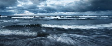 Kışın Baltık Denizi 'nin üzerindeki fırtına bulutları, uzun pozlama. Dramatik günbatımı gökyüzü, dalgalar ve su sıçramaları. Koyu deniz manzarası. Almanya