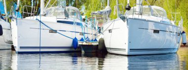 Açık bir yaz gününde, limandaki bir yat limanına demirlemiş beyaz, modern yelkenli tekneleri. Spor ve eğlence teması. İsveç