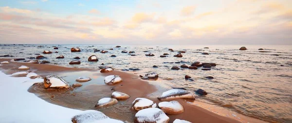 日没の雪に覆われたバルト海沿岸の景色 水の中の石を閉じる カラフルな雲と澄んだ青い空 見事な雲景だ 暖かい夜の光 牧歌的な冬のシーン ラトビアのカルテネ — ストック写真