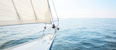 Güneşli bir yaz gününde beyaz bir yat denize açılıyor. Güverteden pruvaya, direğe ve yelkenlere kadar yukarıdan aşağı görüş. Dalgalar ve su sıçramaları. Açık mavi gökyüzü. Finlandiya Körfezi