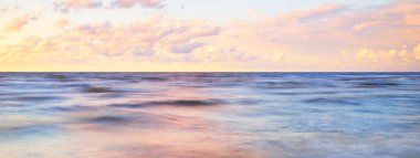 Gök gürültülü bir fırtınadan sonra denizin üstünde destansı pembe gün batımı bulutları. Dramatik bir gökyüzü. Dalgalar ve su dokuya sıçrar. Idyllic deniz manzarası. Kavramsal görüntü, uzun pozlama. Resim gibi bir manzara.