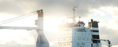 Büyük bir yük vinci gemisi dramatik fırtınalı gökyüzünün altında açık denizde yol alıyor. Destansı deniz manzarası. Nakliye, küresel iletişim, teslimat, yakıt ve güç üretimi, endüstri, lojistik