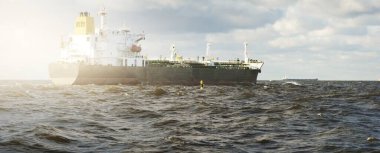 Büyük bir kargo gemisi dramatik fırtınalı gökyüzünün altında açık denizde yelken açıyor. Destansı deniz manzarası. Nakliye, küresel iletişim, teslimat, yakıt ve güç üretimi, endüstri, lojistik