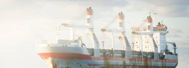 Büyük bir yük vinci gemisi dramatik fırtınalı gökyüzünün altında açık denizde yol alıyor. Destansı deniz manzarası. Nakliye, küresel iletişim, teslimat, yakıt ve güç üretimi, endüstri, lojistik