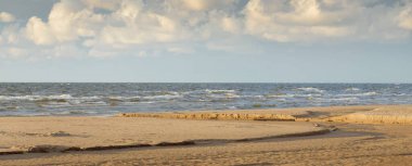 Destansı kümülüs bulutları, fırtınadan sonra kumlu Baltık deniz kıyısında. Kuru nehir, yakın çekim kum dokusu. - Letonya. Dramatik bir gökyüzü. Ekoloji, çevre koruma, kararsız hava, iklim değişikliği