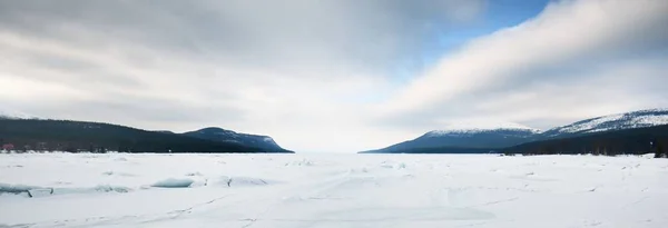 凍結湖の海岸に氷の圧力尾根 背景の山のピーク 劇的な雲景 絵のように美しい冬の風景 生態系 気候変動 地球温暖化の概念 カナダ — ストック写真