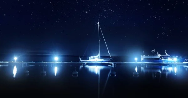 Blue sloop rigged yacht moored to a pier in marina at night. Clear twilight sky, stars, starlight, moonlight, lots of lights. Concept landscape. Copy space, graphic resources. Stockholm archipelago