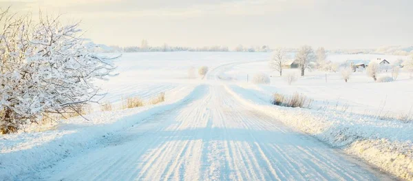 日落时暴风雪过后 乡间小路穿过白雪覆盖的田野 晴朗的天空 金色的光芒 田园诗般的乡村风景 全景全景 圣诞节 危险驾驶 越野车 — 图库照片