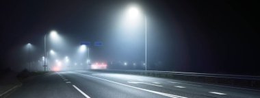 Aydınlatılmış yeni otoyolun panoramik manzarası gece sisli, sokak ışıkları yakın. Ay ışığı. Karanlık şehir manzarası. Avrupa. Ulaşım, lojistik, seyahat, turizm, yol gezisi, özgürlük, sürüş