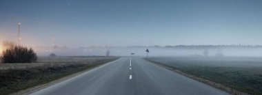 Açık mavi yıldızlı gökyüzü ve geceleri boş otobanın üzerindeki sis. Atmosferik manzara. Idyllic kırsal kesim. Görüntü, sürüş, ulaşım, yolculuk, özgürlük. Panoramik görünüm, boşluğu kopyala