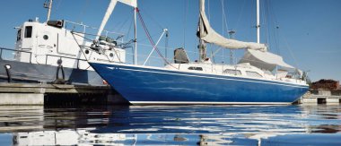 Klasik mavi şalvar donanımlı yat, marinada güneşli kapaklı demirli. Seyahat hayatı, tatil, yelkenli yolculuğu, yelkencilik, eğlence, eğlence aktivitesi, spor, ulaşım, su yüzeyi dokusu