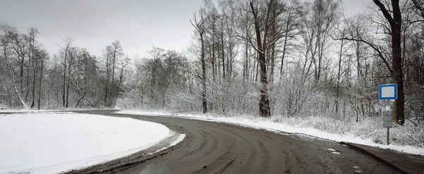 乡间公路有一个交汇处 车辙在尘土飞扬的雪地里特写 在多云的冬日 森林的道路上 从巴士站看到的风景 危险驾驶 冬季轮胎 偏远地区 — 图库照片