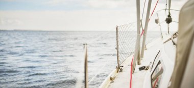 Güneşli bir günde Kuzey Denizi 'nde yelken açan beyaz bir yat. Açık mavi gökyüzü suya yansıyor. Arka planda fiyortlar var. Rogaland bölgesi, Norveç. Spor, eğlence, eğlence etkinlik teması