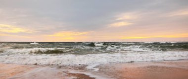 Gün batımında Anholt Adası 'nın kumsal kıyısında. Dalgalar ve su sıçramaları. Renkli bulutlu bir manzara. Çevre koruma, eko turizm teması. Kattegat, Danimarka