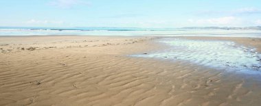 Douarnenez körfezinin kumlu sahilinden bir manzara. Açık mavi gökyüzü. Sudaki yansımalar. Dalgalar ve su sıçramaları. Brittany, Fransa. Seyahat yerleri, boş zaman etkinlik teması