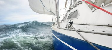 Yağmurlu bir günde, fırtınalı bir havada yat gezintisi. Güverteden pruvaya, direğe ve yelkenlere yakın görüntü. Dramatik fırtınalı gökyüzü, kara bulutlar. Dalgalar ve su sıçramaları. Kötü hava. Baltık Denizi, İsveç