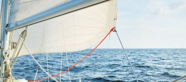 Güneşli bir günde açık denizde beyaz yelkenli, güverteden pruvaya yakın görüntü, direk ve yelkenli. Tek başına 10 metrelik bir yata biniyor. İngiltere, İngiltere. Spor, yarış, eğlence.