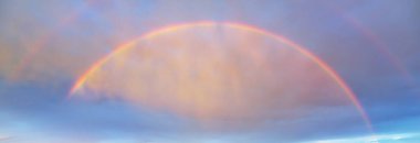 Çifte gökkuşağı ve yağmurdan sonra parlayan renkli bulutlarla dramatik günbatımı gökyüzü. Destansı bulut manzarası. Hava kararsız. Kasırga, fırtına, meteoroloji, ekoloji, doğa