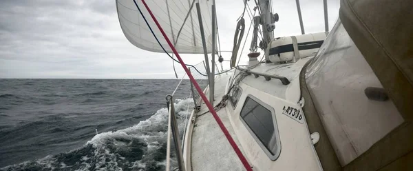游艇在雷雨中航行 从甲板到船头 桅杆和船帆的近景 戏剧化的暴风雨天 浪花和水花四溅 恶劣的天气 瑞典波罗的海 — 图库照片