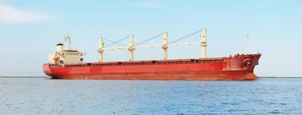 ヨーロッパ港から外洋を航行するクレーン付き大型赤色ばら積み貨物船 貨物船 白色の雲で青空をきれいにする オランダのロッテルダム グローバルコミュニケーション 産業テーマ — ストック写真