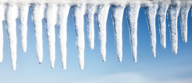 Büyük buz saçakları yakın plan. Açık mavi gökyüzü. Kış manzarası kavramı. Gün ortası güneşi. Mevsimler, ekoloji, çevre, iklim değişikliği, küresel ısınma, anomali, doğa. Panoramik görünüm, boşluğu kopyala