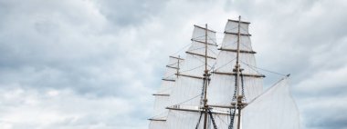 Kırpıcı uzunluğundaki geminin antik ahşap ölçekli modeli, yakın plan. Arka planda dramatik gökyüzü ve deniz kıyısı. Geleneksel zanaat, hediyelik eşya, hobi, koleksiyon, antika, modellik. Sıfır atık