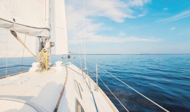 Günbatımında beyaz yelkenli tekneyle denize açılacak. Fırtınadan sonra gökyüzü açık. Güverteden pruvaya, direğe, yelkenlere bakın. Ulaşım, seyahat, gezi, spor, eğlence, boş zaman aktivitesi, yarış, yelkenli yarışı